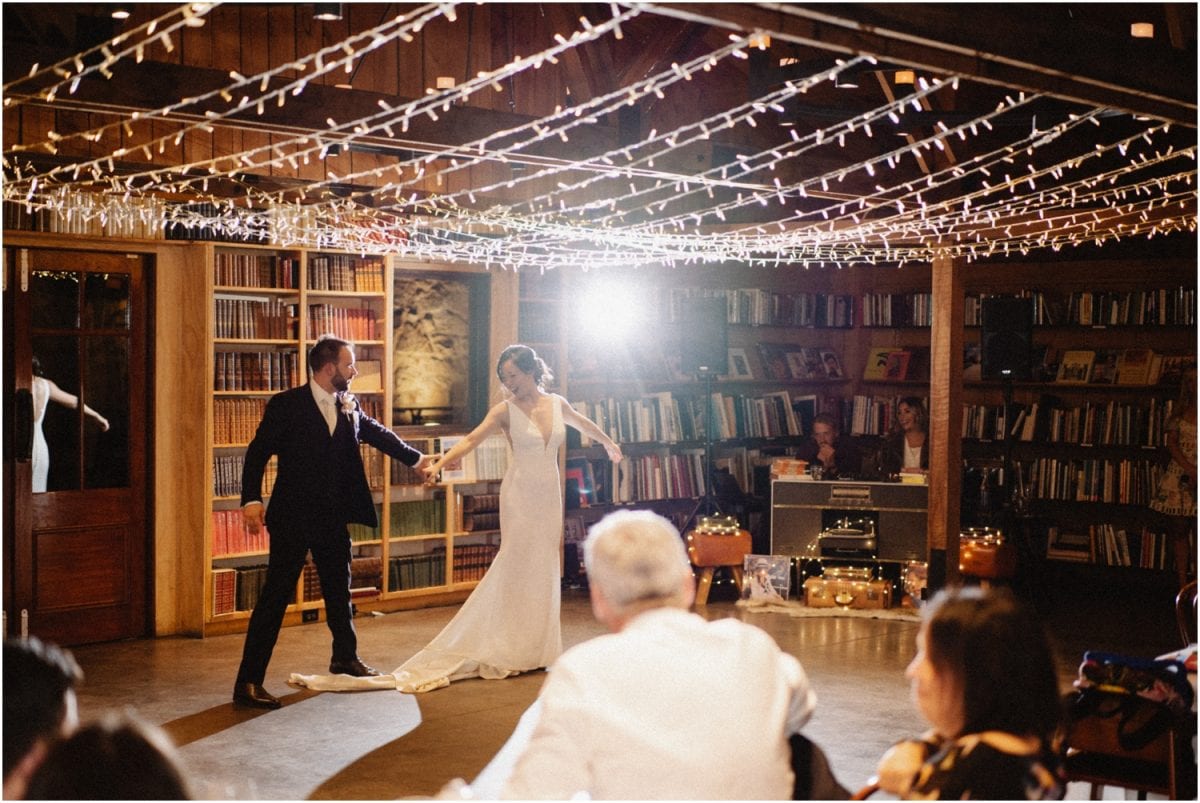 A newly married bride and groom do their first dance amongst walls of booked at their Bendooley wedding