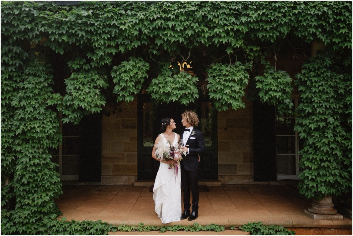 A newly married couple stand in front of the Homestead at their Bendooley Estate Book Barn wedding